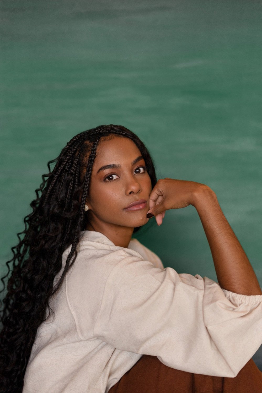 Anna Alice Vieira, psicóloga, diante de uma parede verde, olhando para a câmera